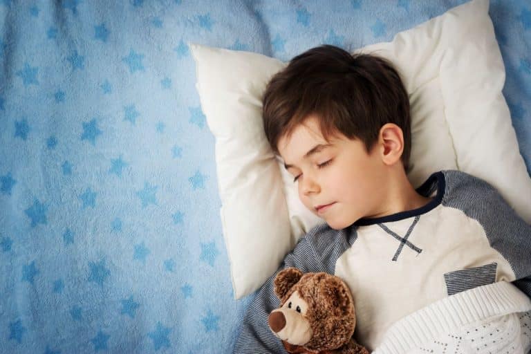 Pediatric-snoring-treatment Child sleeping in bed with a teddy bear tucked under their arm